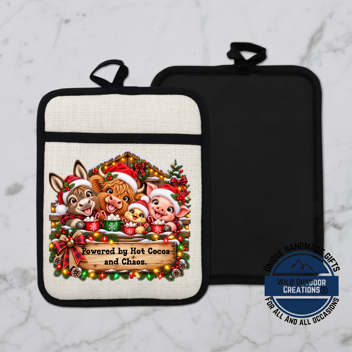 A white and black pot holder with a Christmas-themed design featuring a donkey, pig, and chicken, along with the text "Powered by Hot Cocoa and Chaos".
