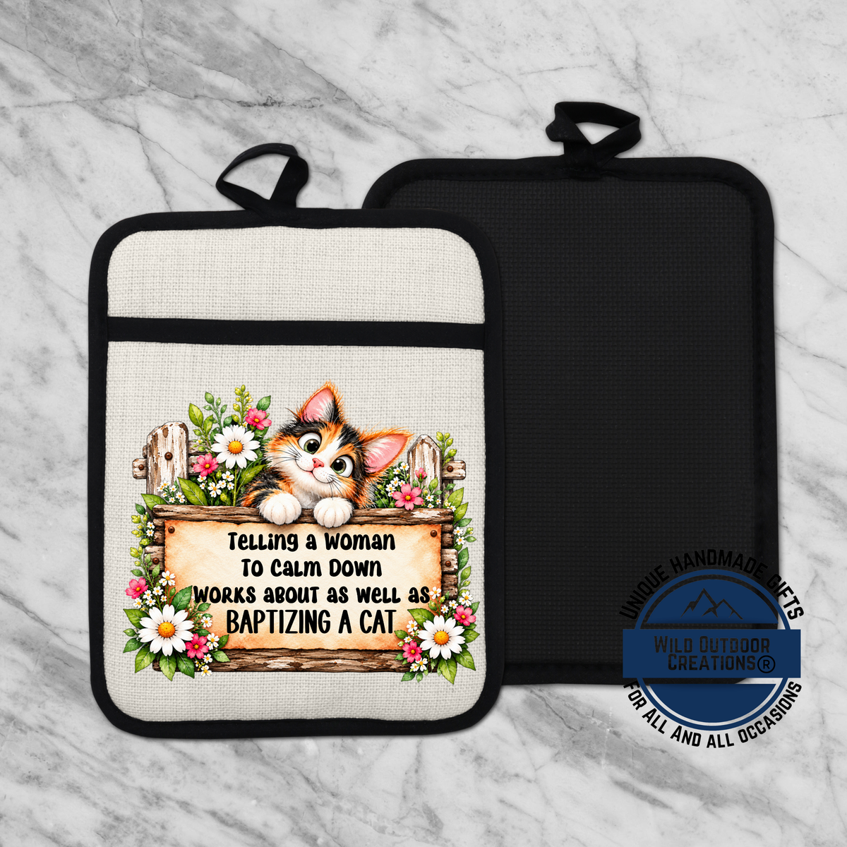 A beige oven mitt with a black handle and a white and black floral design on it, featuring a cartoon cat and text that says "Telling a woman to calm down works about as well as baptizing a cat".