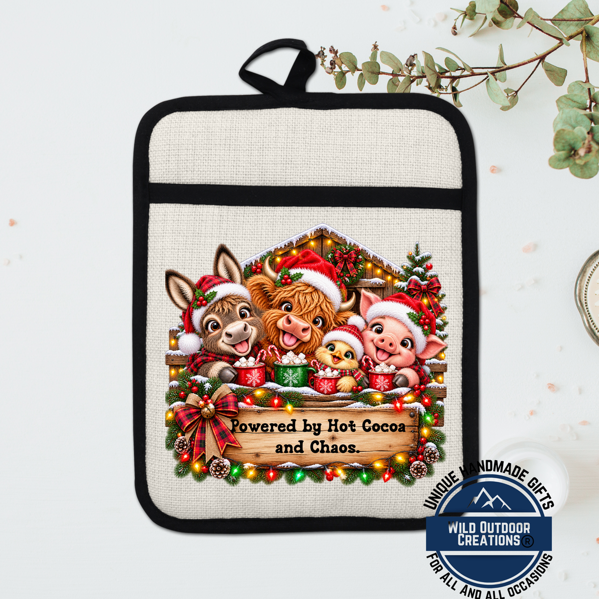 A hand-painted pot holder featuring a festive scene with three cartoon animals wearing Santa hats, surrounded by Christmas decorations and a sign that says "Powered by Hot Cocoa and Chaos".