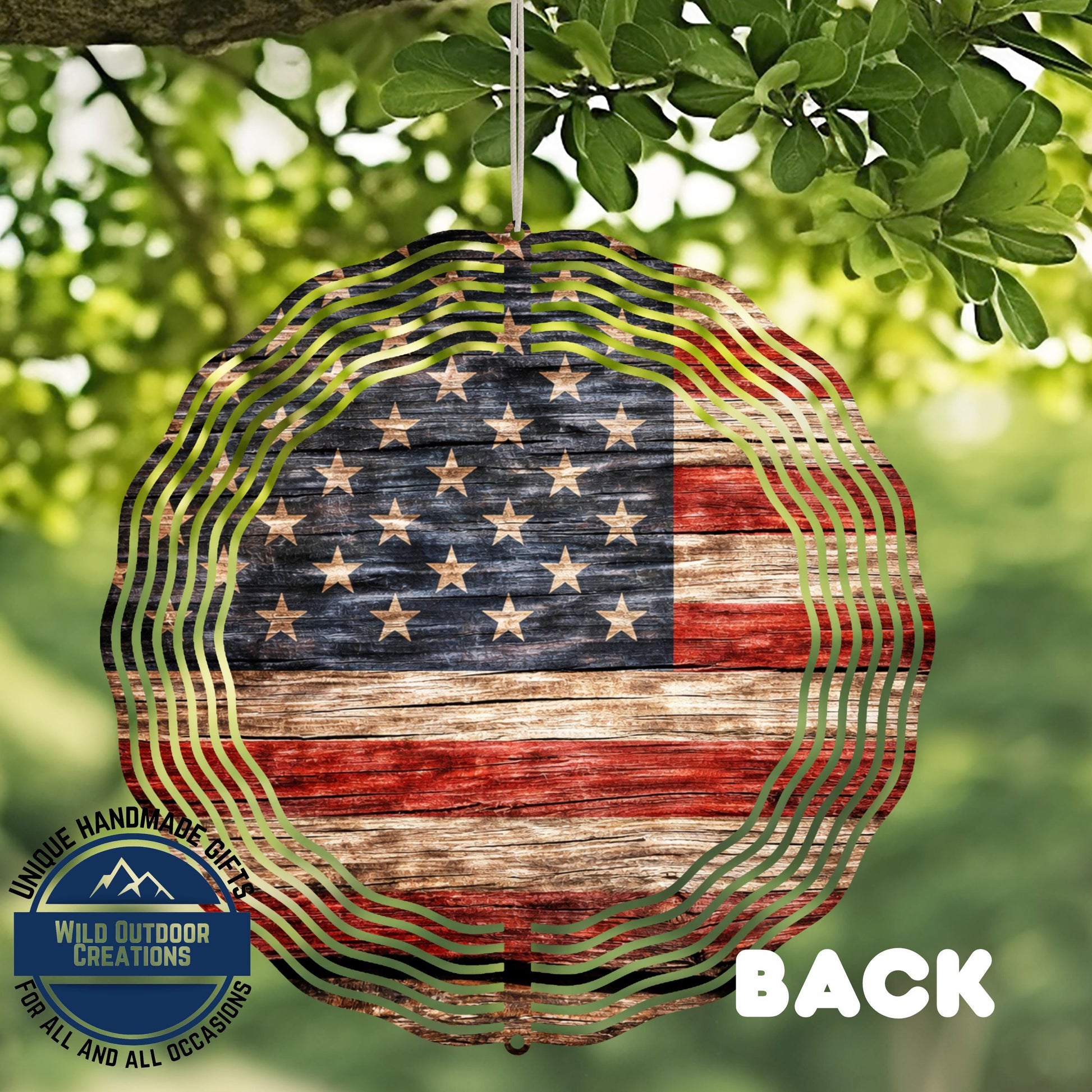 a patriotic American flag-themed wind chime hanging from a tree branch.