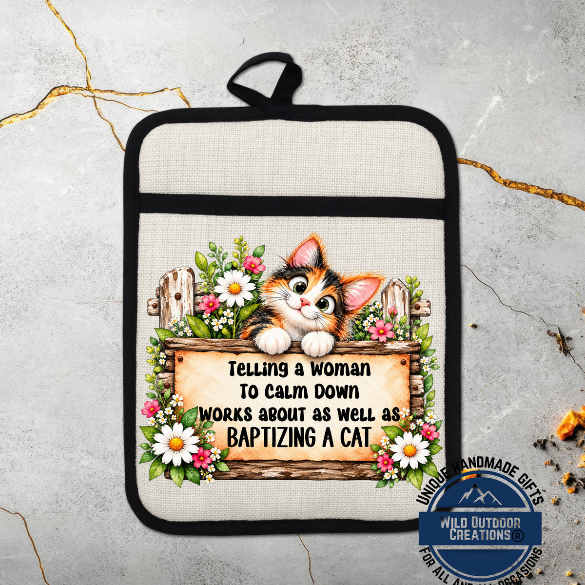 A beige oven mitt with a cartoon cat design and text that says "Telling a woman to calm down works about as well as baptizing a cat".