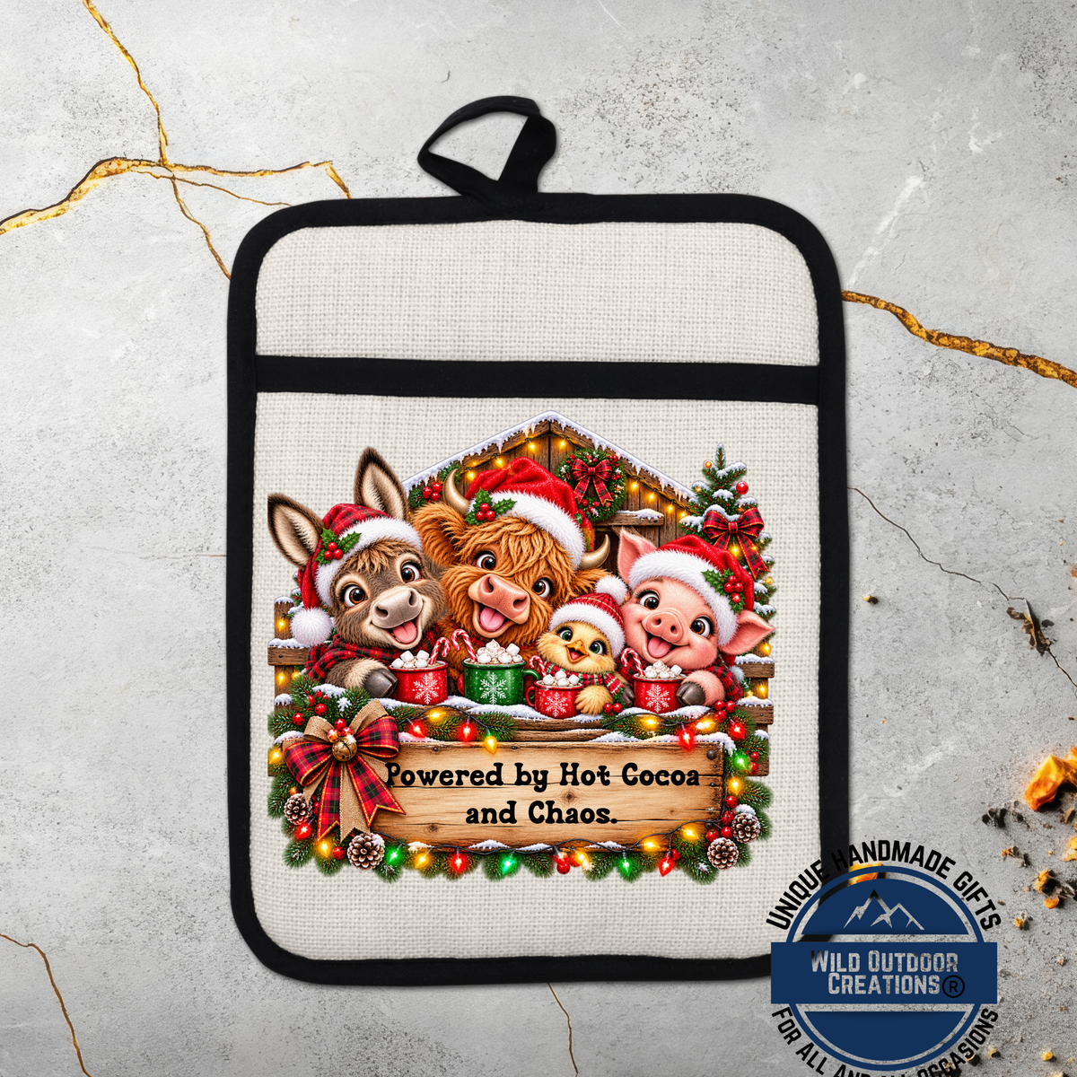 A hand-made pot holder featuring a festive Christmas scene with cartoon animals, including a pig, cow, and chicken, all wearing Santa hats and scarves. The pot holder is decorated with Christmas lights and a banner that reads "Powered by Hot Cocoa and Chaos".