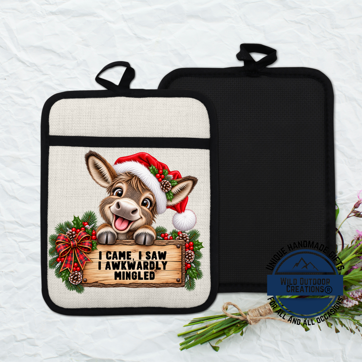 A pot holder with a cartoon donkey wearing a Santa hat and holding a sign that says "I came, I saw, I Awkwardly Mingled".