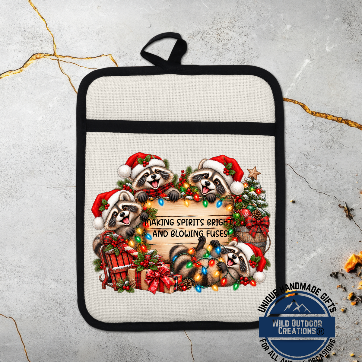 A beige oven mitt with a black handle, featuring a festive design of raccoons wearing Santa hats and surrounded by Christmas decorations such as a Christmas tree, presents, and lights.