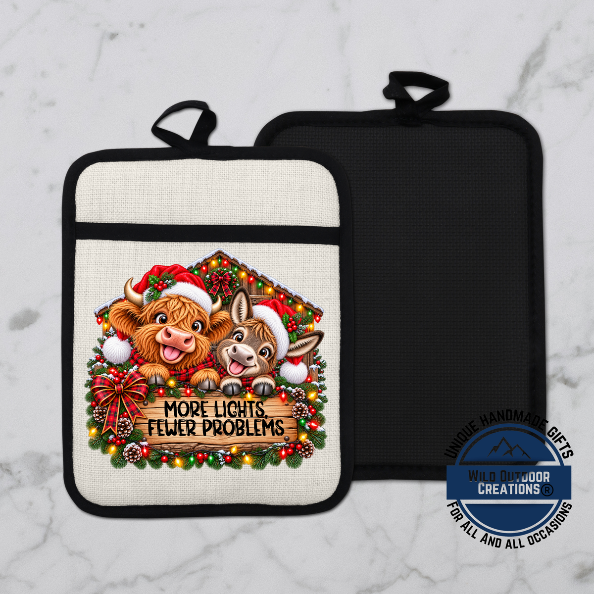 a white and black pot holder with a Christmas-themed design. The pot holder has a black handle and a white background. The design includes two cartoon animals, a cow and a dog, wearing Santa hats and surrounded by Christmas decorations. The text on the pot holder reads "MORE LIGHTS FEWER PROBLEMS" and "UNIQUE HANDMADE GIFTS WILD OUTDOOR CREATIONS FOR ALL AND ALL OCCASIONS".