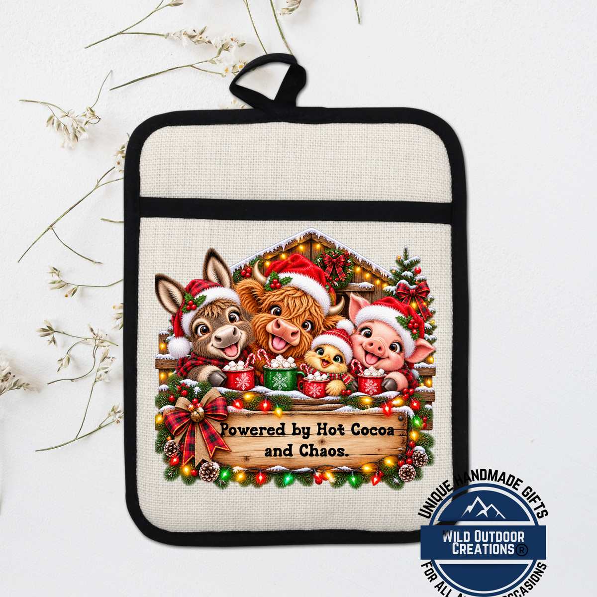A hand-made pot holder featuring a festive Christmas scene with cartoon animals, including a pig, cow, and rabbit, wearing Santa hats and holding cups of hot cocoa.