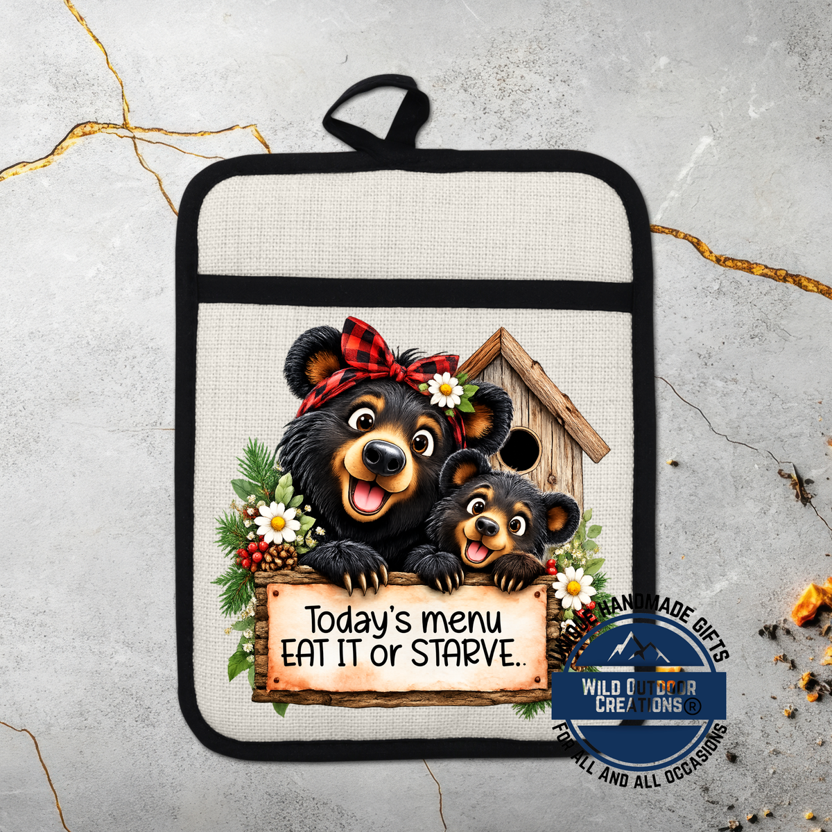 A kitchen pot holder with a cartoon image of two black bears, one larger and one smaller, sitting together and smiling. The pot holder has a sign that says "Today's menu eat it or Starve."
