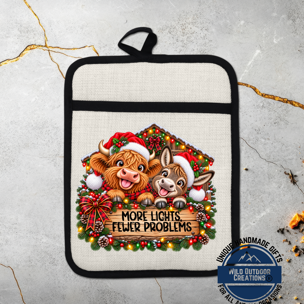 A beige oven mitt with a Christmas-themed design featuring two cartoon cows wearing Santa hats and surrounded by a wreath of lights and pine cones. The text on the mitt reads "MORE LIGHTS FEWER PROBLEMS".