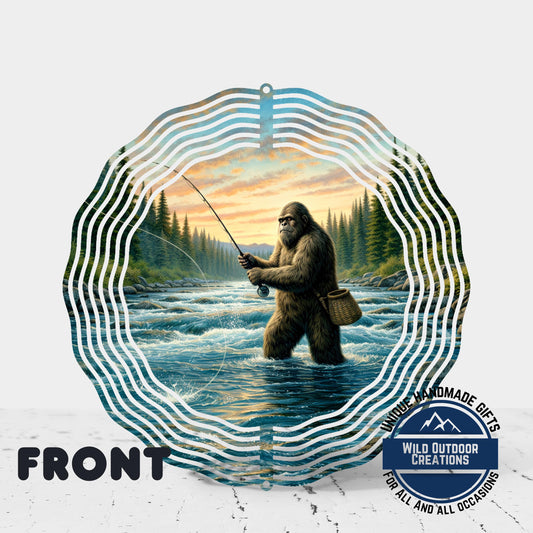 A large, circular wind chime with a painting of a giant brown creature, possibly a Sasquatch, fishing in a river surrounded by trees and mountains.