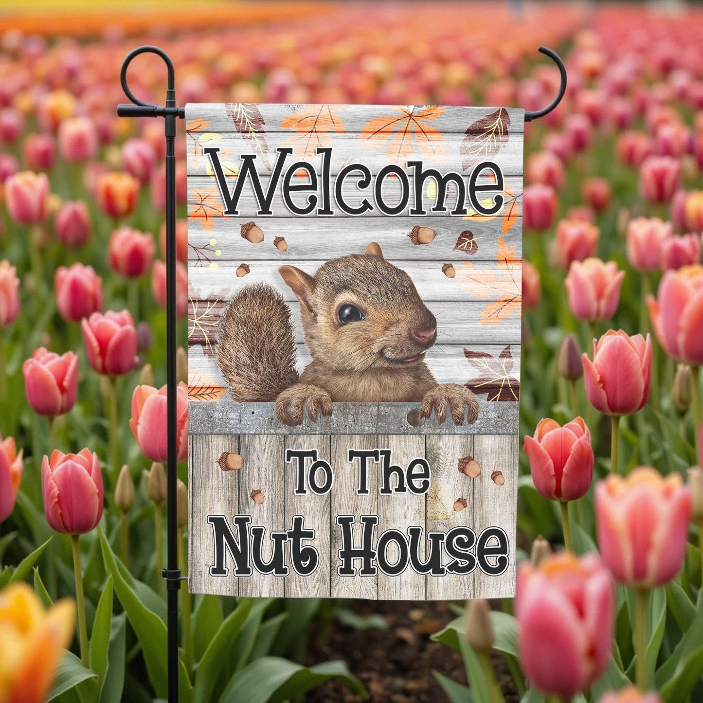 A garden flag with a squirrel on it, displaying the text "Welcome to the Nut House".