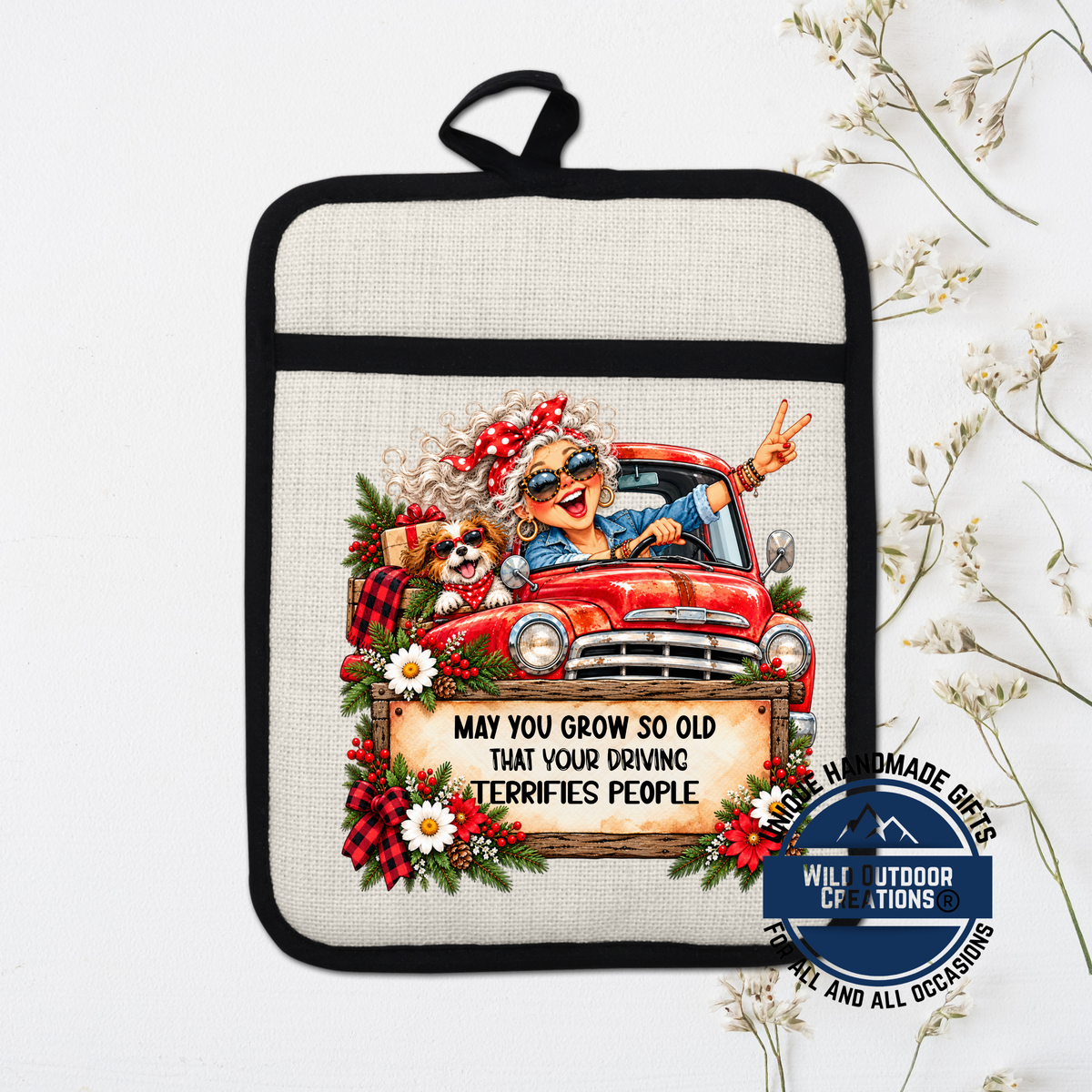 A hand-made pot holder with a cartoon image of an elderly woman driving a red truck, accompanied by a sign that says "May you grow so old that your driving terrifies people".