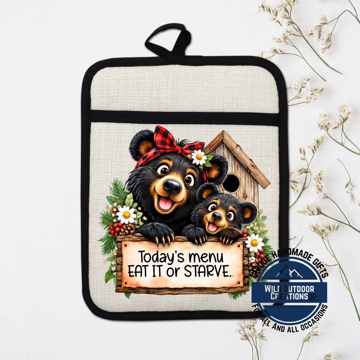 A kitchen pot holder with a cartoon image of two bears, one larger and one smaller, peeking out from behind a wooden birdhouse. The bears are wearing red and black plaid bows. The pot holder has a sign that says "Today's menu eat it or Starve."