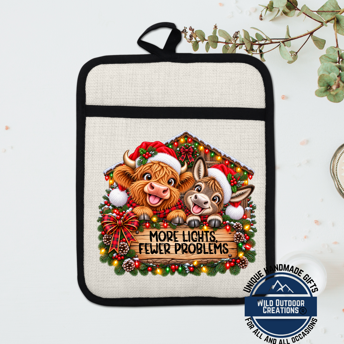 A beige oven mitt with a Christmas-themed design featuring two cartoon cows wearing Santa hats and surrounded by holiday decorations.