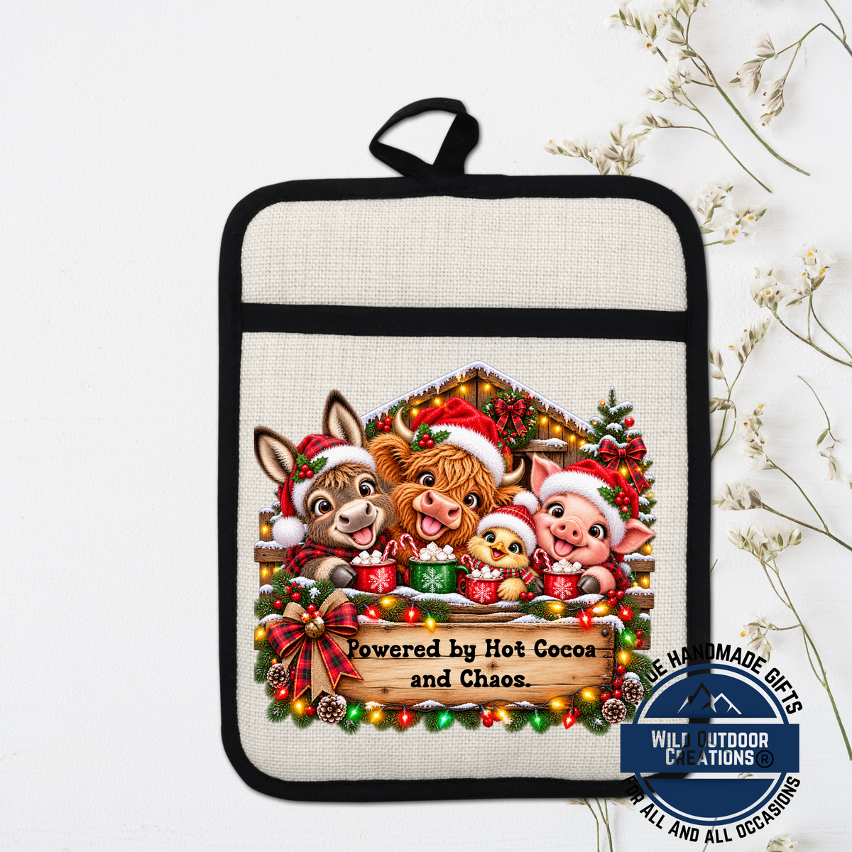 A hand-made pot holder featuring a festive Christmas scene with cartoon animals, including a donkey, pig, and chicken, all wearing Santa hats and holding cups of hot cocoa. The pot holder is decorated with Christmas lights and a wreath, and the text "Powered by Hot Cocoa and Chaos" is displayed.