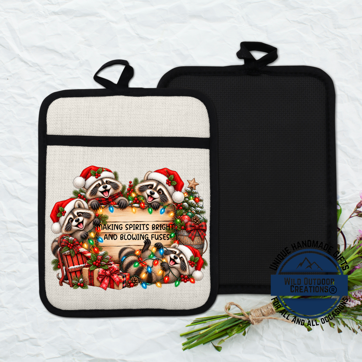 A beige pot holder with a Christmas-themed design featuring raccoons wearing Santa hats and surrounded by holiday decorations such as a Christmas tree, presents, and ornaments.