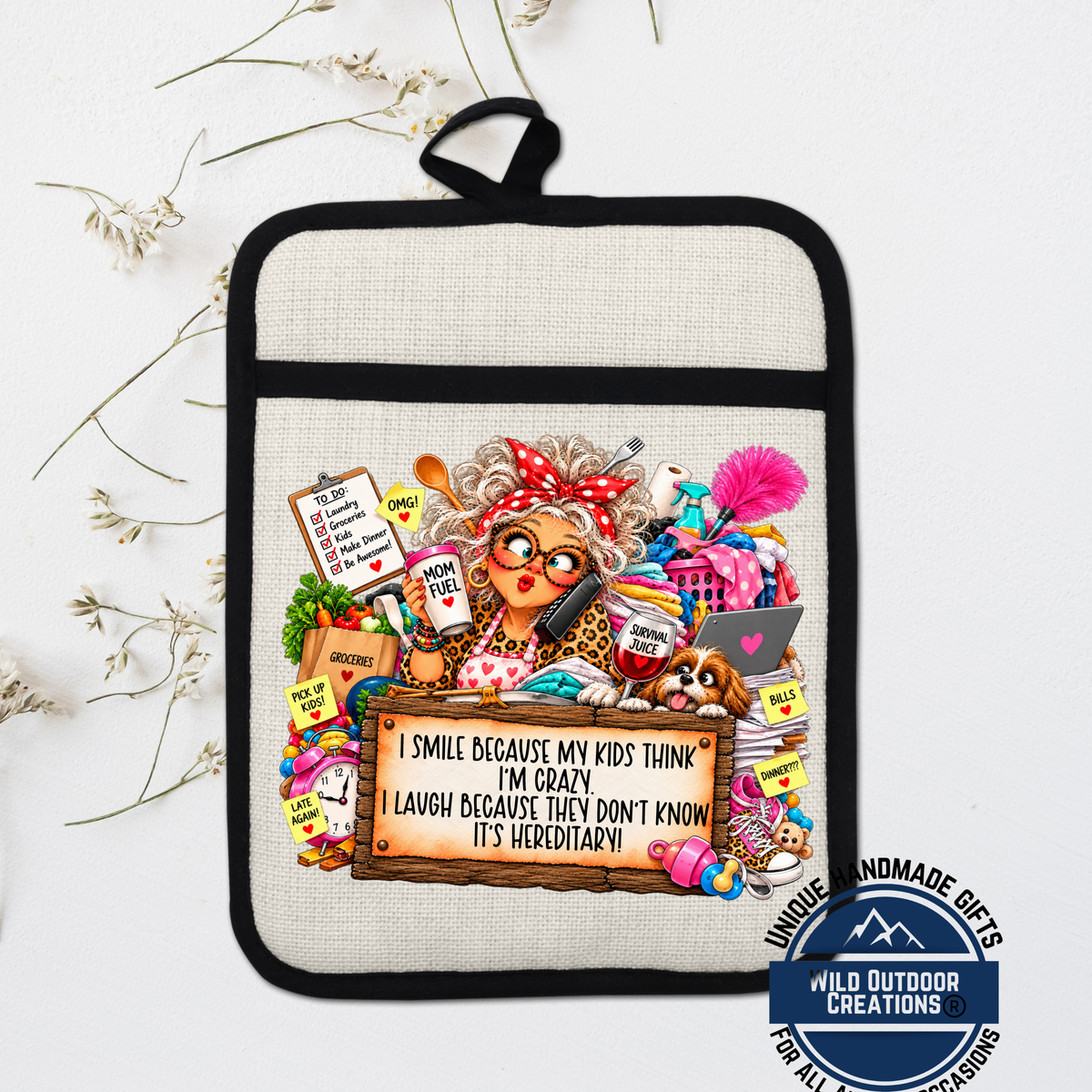 A hand-made pot holder with a cartoon illustration of a woman with curly hair, wearing glasses and a red bow, surrounded by various objects such as a laptop, books, and a sign that says "I smile because my kids think I'm crazy, I laugh because they don't know it's hired!"