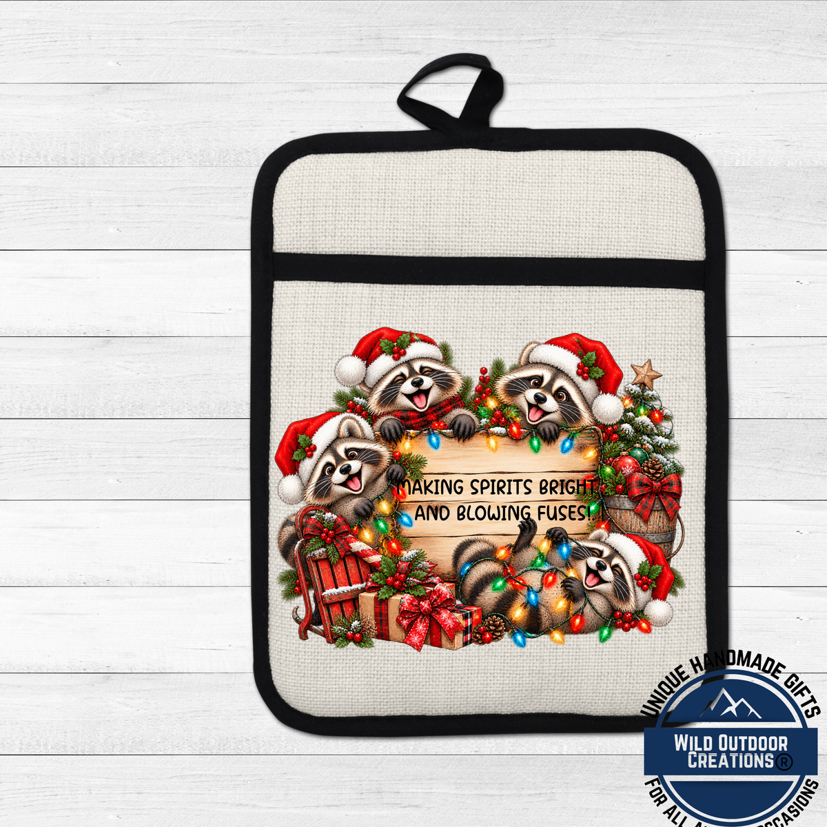A beige oven mitt with a black handle, featuring a festive Christmas-themed design with raccoons wearing Santa hats and holding a sign that says "Making Spirits Bright and Blowing Fuses".