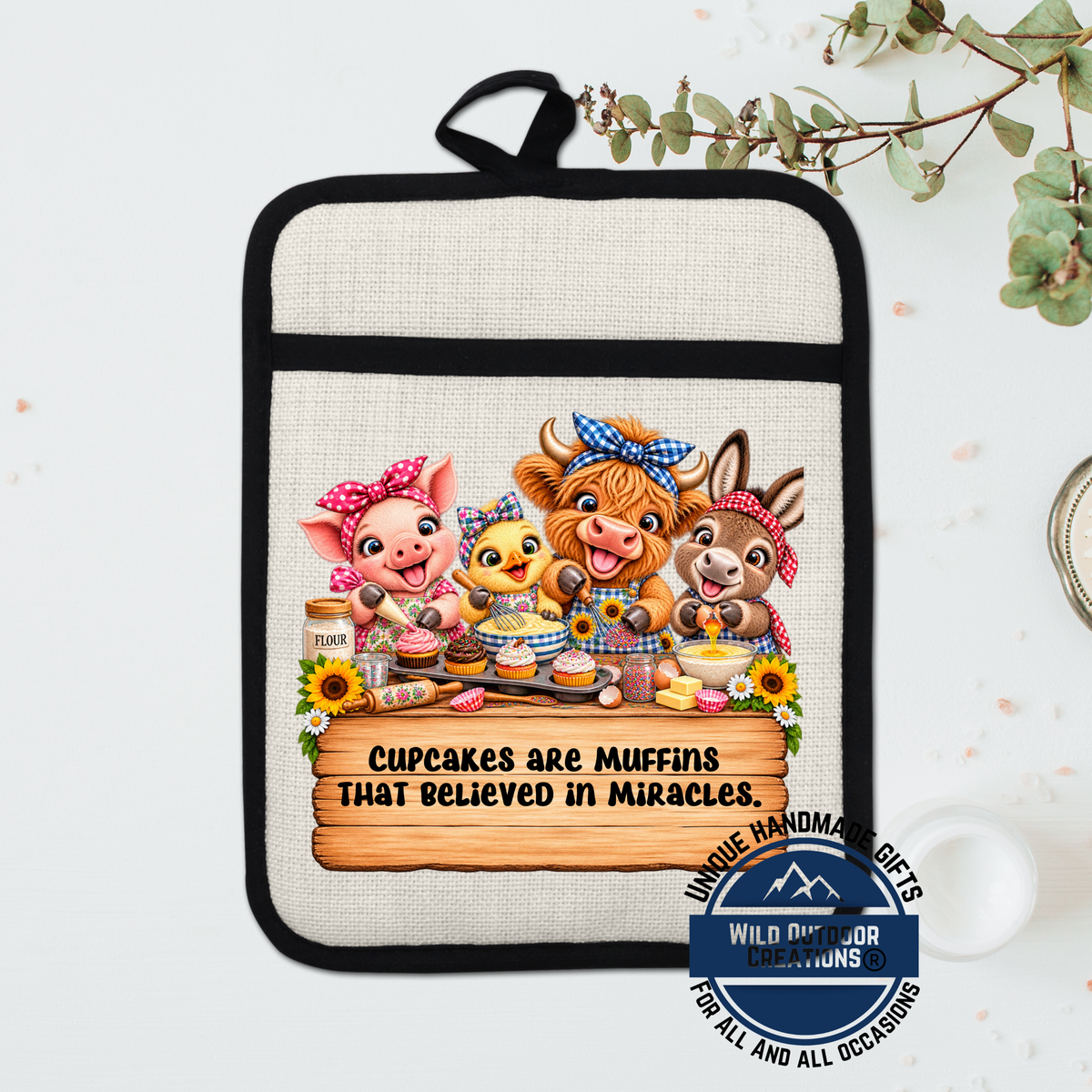 A kitchen pot holder with a cartoon illustration of four animals, including a pig, cow, chicken, and rabbit, along with the text "Cupcakes are muffins that believed in miracles."