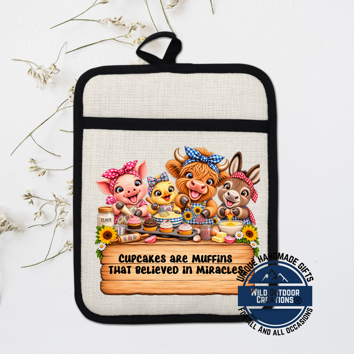 A hand-made oven mitt with a cartoon illustration of four cute animals, including a pig, cow, chicken, and rabbit, along with the text "Cupcakes are Muffins that believed in Miracles".