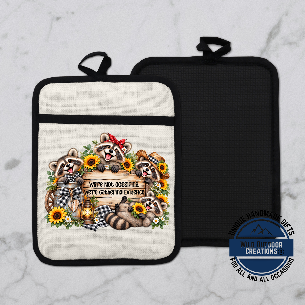 a white pot holder with a black handle, decorated with a playful design of raccoons and sunflowers.