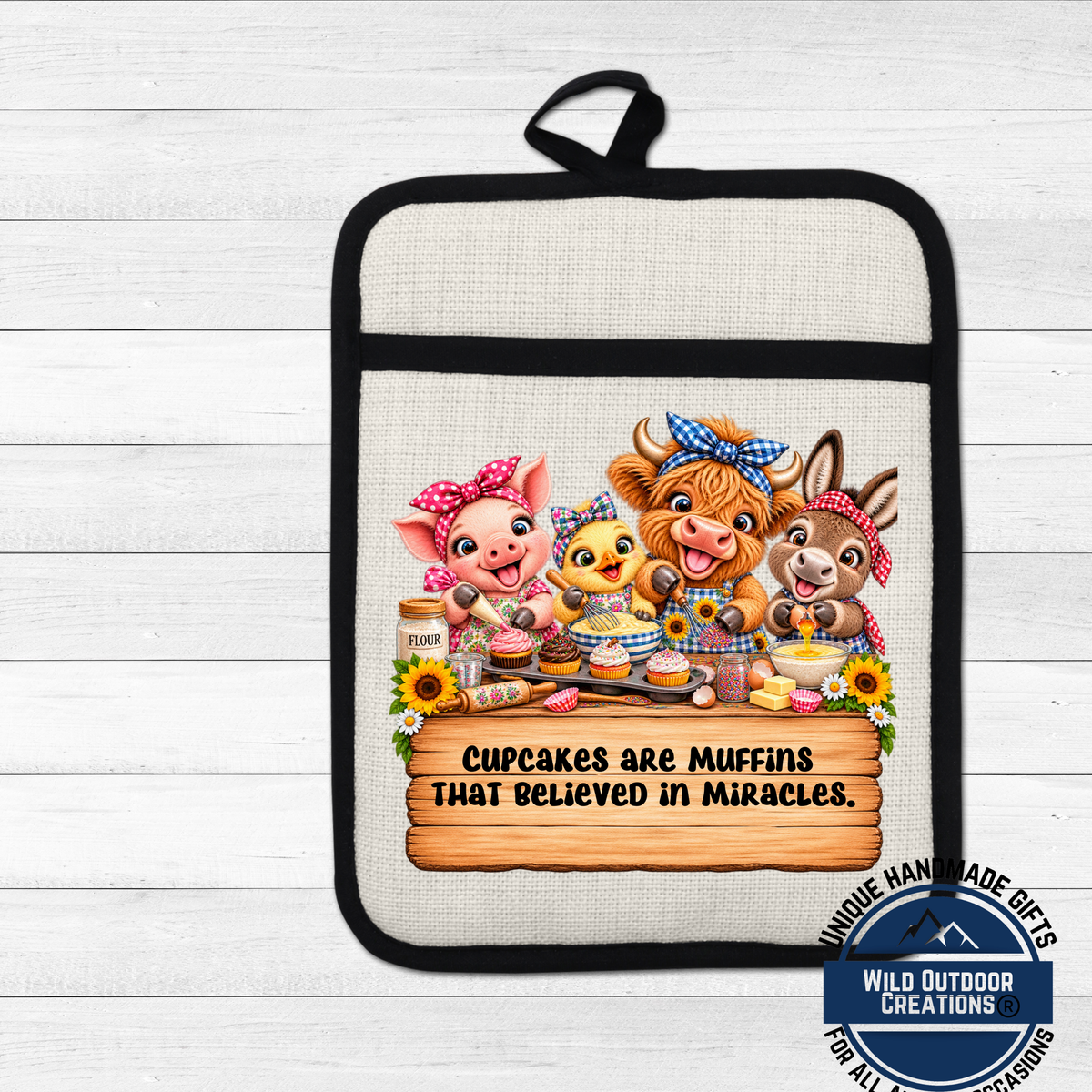 A hand-made oven mitt featuring a cartoon illustration of a pig, cow, and duck with the text "Cupcakes are muffins that believed in miracles" and a wooden sign with the phrase "Cupcakes are muffins that believed in miracles."